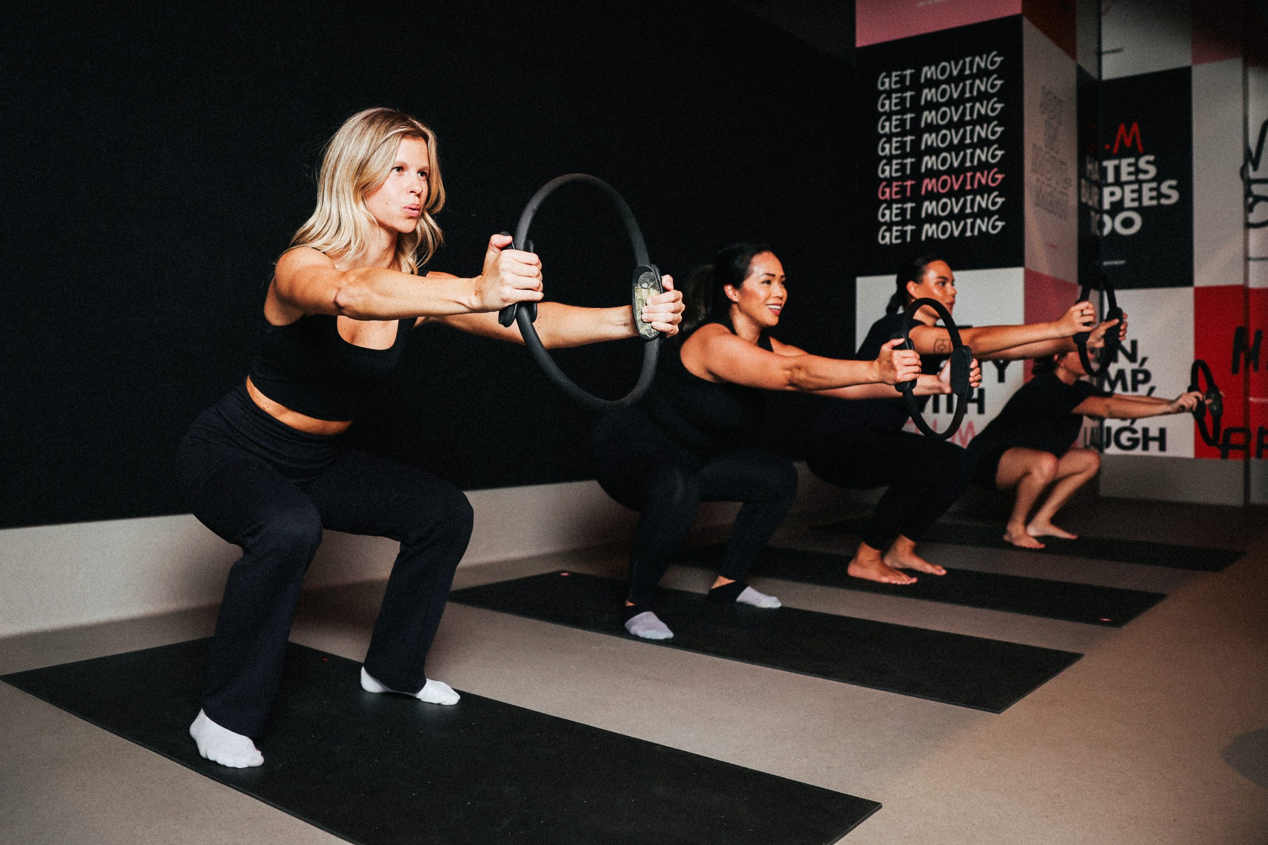 Members holding Pilates rings out in front, following the screen